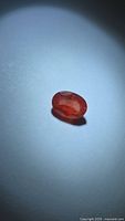 Oval deep orange-pink sapphire front view