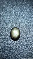 Oval black star sapphire on textured background showing star