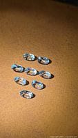 Group of nine light blue oval aquamarine stones on brown surface