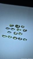 Group of 14 lemon-lime tanzanite gemstones on white surface