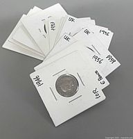 Stack of 13 coin flips showing handwritten years 1953, 1956, 1938, 1949 and others