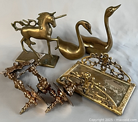 Group shot of all brass items including unicorn, two swans, ornate tray and four hardware pieces