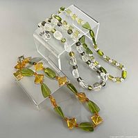 All three necklaces displayed on risers showing colors, shapes and overall style