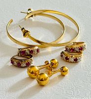 overview of three earring pairs: large hoops, gemstone huggies, barbell studs