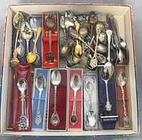 Top view of box containing approximately 50 assorted souvenir teaspoons, some boxed