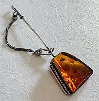 Full view of stick pin showing amber cabochon and safety chain