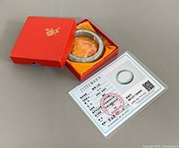 Bangle inside red box with yellow lining and certificate card