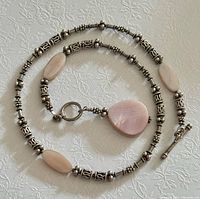 Full necklace coiled showing rose quartz beads, silver beads, and toggle clasp