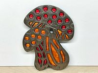 Front view of mushroom-shaped trivet showing coloured inserts