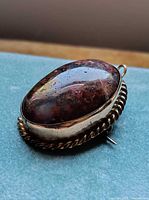 Front angled view showing moss agate cabochon and rope-twist frame