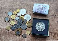 Overview of assorted coins, folded banknotes, British crown in box