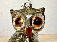 front view of glass owl ornament showing eyes, beak, glitter accents, hanging cap