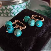 Front view of both gold rope-loop charms with turquoise bead drops