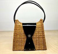 Front view showing wicker body, leather flap, handle