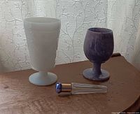 Group shot of stone goblet, milk glass vase, perfume bottle