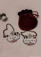 Front view of both enamel labels, chains, pouch and metal cylinder