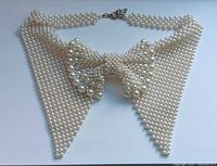 Front view of woven faux pearl necklace showing bow motif and clasp