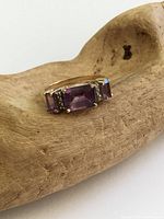 Front view of 10K gold ring showing center emerald-cut amethyst, side amethysts, and diamond accents