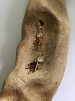 Two 10 k gold gem-set charms on driftwood background