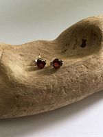 Both garnet stud earrings on wooden display