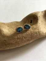 Front view of stud earrings showing opal cabochons and gold settings