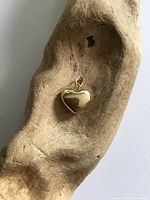 Front view of 14K gold puffy heart pendant on wood prop