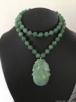 Entire necklace displayed on bust showing bead strand and pendant