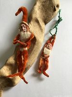 Both antique chenille Santa ornaments displayed on driftwood
