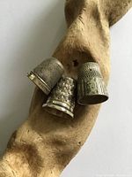 Three sterling silver thimbles on driftwood display