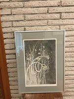 Full view of framed print against brick wall