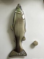 Full front view of fish-shaped metal flask, cap removed