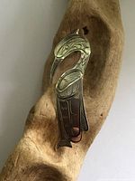 Front view of sterling carved bird brooch on driftwood