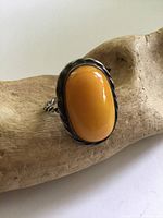 Front view of ring displaying oval butterscotch amber cabochon in silver bezel