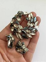 Brooch and earrings in hand showing size, stones and setting