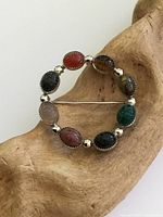 Front view of round sterling silver brooch with eight gemstone scarabs