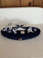 All crystal figurines arranged on blue velvet pad with SCS plaque