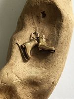 Front view of gold figure skates charm on wood background