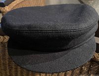Front view of black wool cabbie hat showing brim and crown