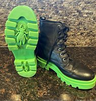 Boots upright, one showing sole with fly logo