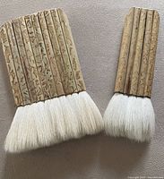Two goat hair wet mounting brushes with bamboo handles displayed on flat surface
