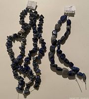 Group of six blue lapis bead strands on wall hooks