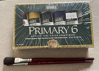 Front of sealed Liquitex Primary 6 paint set with two brushes below