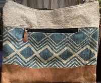Front view showing hair-on cowhide upper, woven cotton geometric pattern, leather base, zip pocket