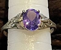 Top view of silver ring with oval amethyst and bird motifs