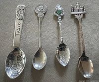 Front view of four souvenir spoons showing decorative handles and bowls