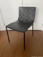 Front three-quarter view of woven black faux leather dining chair showing overall design