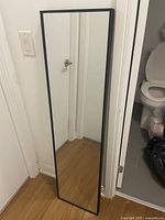 Full view of mirror standing against wall showing entire frame and glass