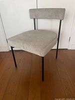 Front angle view of grey chenille dining chair showing seat, backrest and black metal legs