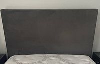 Front view of grey velvet headboard attached to bed frame