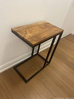 Full view of side table against wall showing wood top and L-shaped metal base